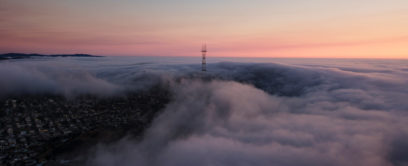 Sutro Tower peaking through fog and clouds over Buena Vista Park, San Francisco